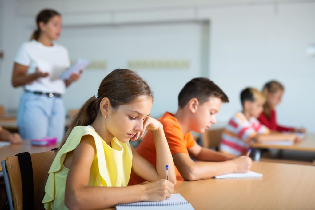 Écolière qui écrit des exercices dans son cahier à l’école Michelet