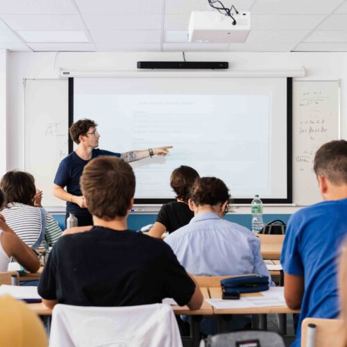 Enseignant donnant un cours devant un tableau interactif à une classe d’étudiants attentifs en classe prépa scientifique, dans une salle de cours lumineuse du lycée privé Michelet à Nice.